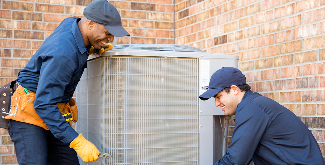 Two technicians working on an AC unit